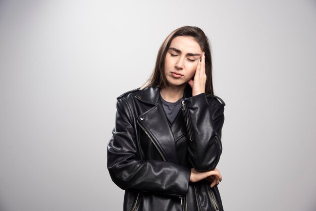 Foto de una hermosa mujer tocando su cabello en chaqueta de cuero negro