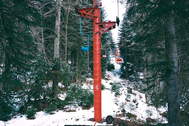 Foto gratuita foto de hermoso y pequeño telesilla con sillas de colores, moviéndose a través del bosque de invierno en las montañas