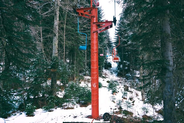 Foto de hermoso y pequeño telesilla con sillas de colores, moviéndose a través del bosque de invierno en las montañas