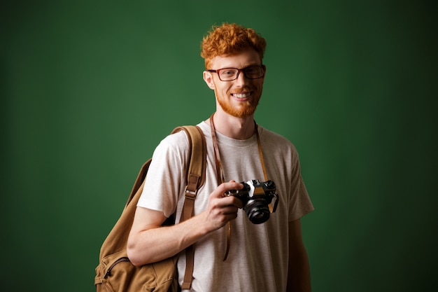 Foto de hipster barbudo de cabeza lectora con cámara retro y mochila