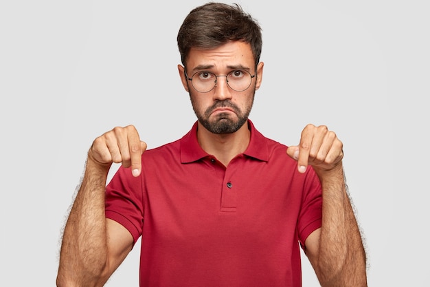 Foto de hombre disgustado con expresión facial negativa frunce los labios