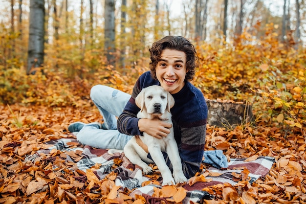 Foto de hombre guapo y su perro pasan tiempo en el bosque de otoño.