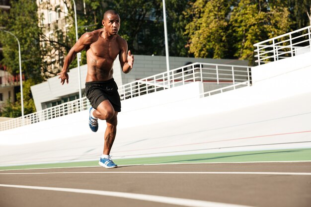 Foto de hombre joven atleta afroamericano en pista de atletismo al aire libre