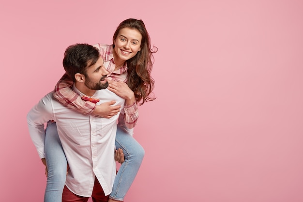 Foto de hombre juguetón dando caballito a su novia