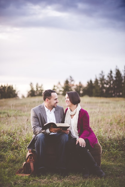 Foto de hombre leyendo un libro a la mujer bajo el cielo nublado gris