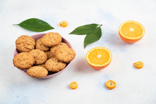 Foto horizontal de galleta casera en tazón rosa y naranja medio cortada sobre superficie blanca.