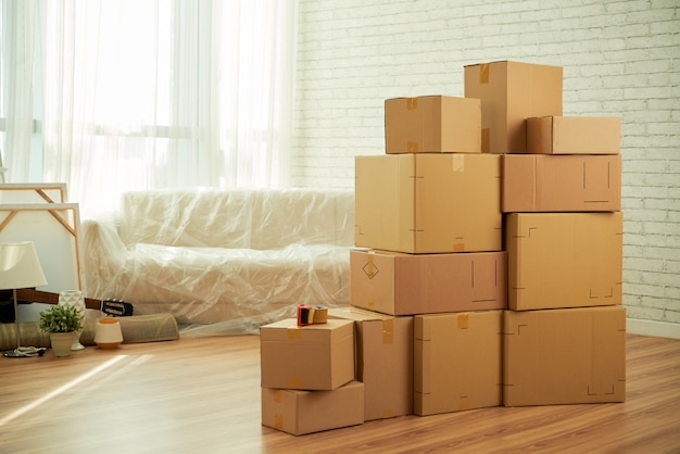 Foto del interior de la habitación con cajas de paquetes en el medio y sofá cubierto con película