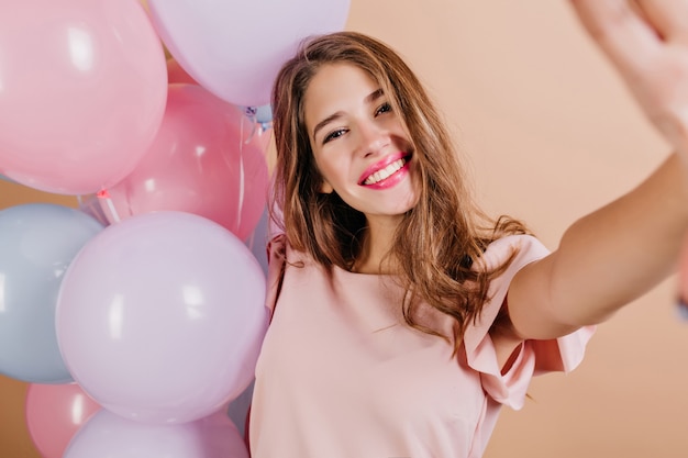 Foto interior de linda mujer con peinado largo haciendo selfie después de la fiesta de cumpleaños