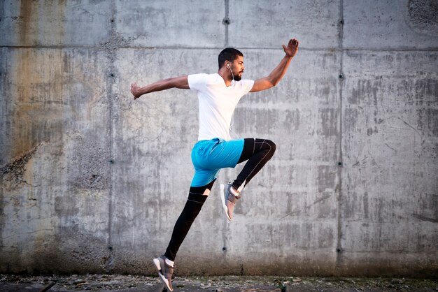 Foto de joven atleta deportivo saltar contra el fondo de la pared de hormigón