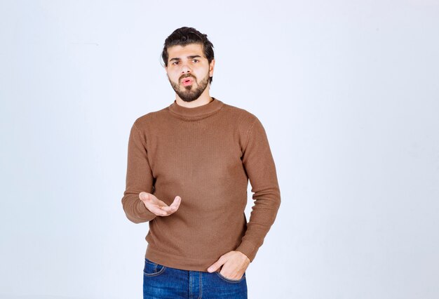 Foto de un joven atractivo modelo de pie y posando sobre una pared blanca. Foto de alta calidad