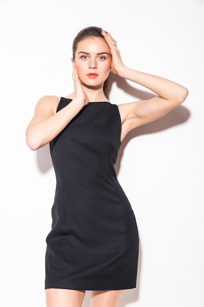 Una foto de una joven y bella mujer con un vestido negro posando sobre fondo blanco.