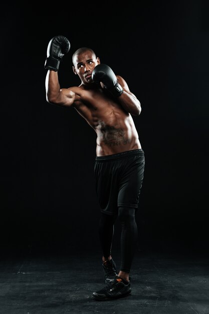 Foto del joven boxeador afroamericano, de pie en pose de protección