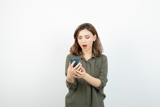 Foto de una joven con un celular de pie y revisando sus mensajes. foto de alta calidad