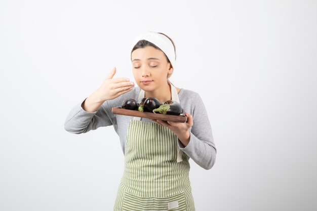 Foto gratuita foto de joven cocinera huele berenjenas en blanco