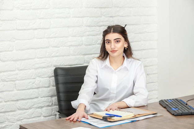 Foto de una joven empresaria sentada en el escritorio y mirando a la cámara Foto de alta calidad