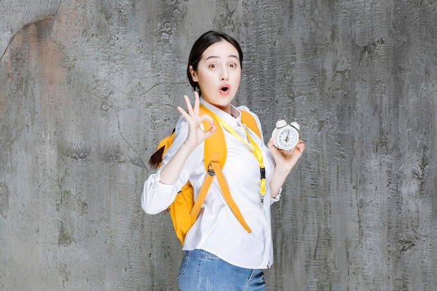 Foto de joven estudiante con mochila que muestra la hora en el reloj. foto de alta calidad