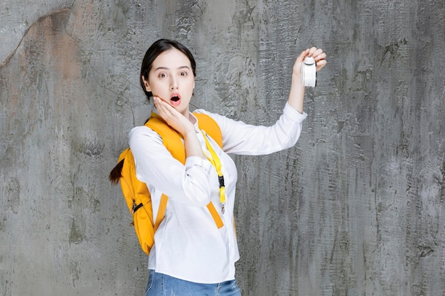 Una foto de una joven estudiante con mochila con reloj se dio cuenta de que se estaba haciendo tarde. foto de alta calidad