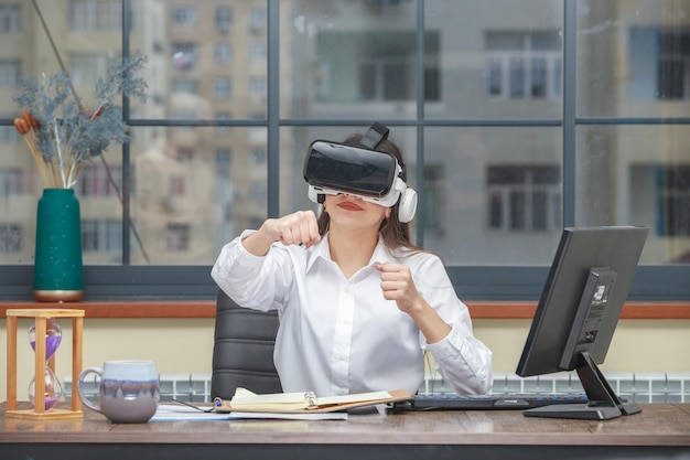 Foto de una joven con gafas de realidad virtual y apretando los puños