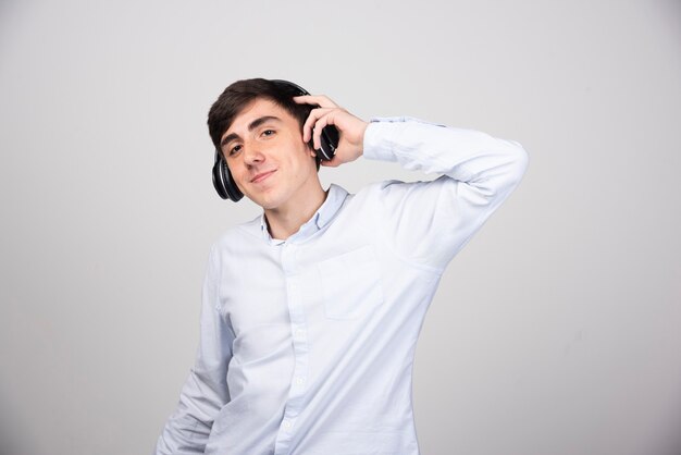 Foto de un joven modelo escuchando música en auriculares inalámbricos