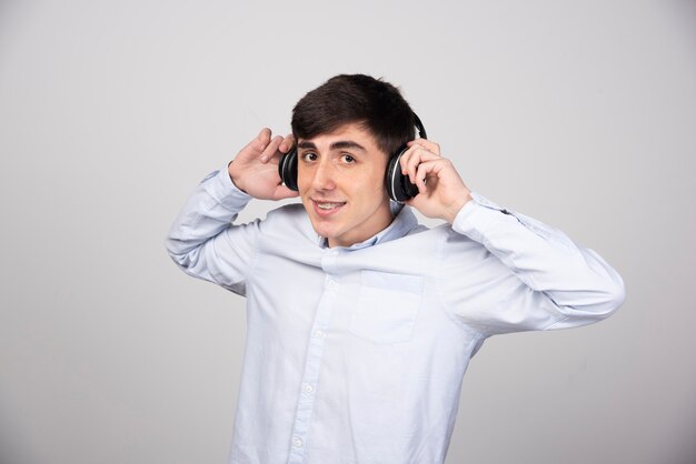 Foto de un joven modelo escuchando música en auriculares inalámbricos