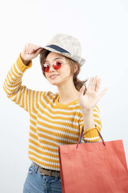 Foto de una joven morena con gafas de sol sosteniendo una bolsa de compras. foto de alta calidad