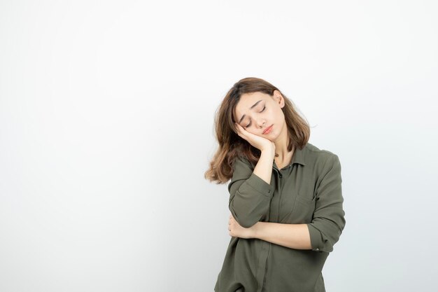 Foto de una joven parada y durmiendo sobre una pared blanca. foto de alta calidad