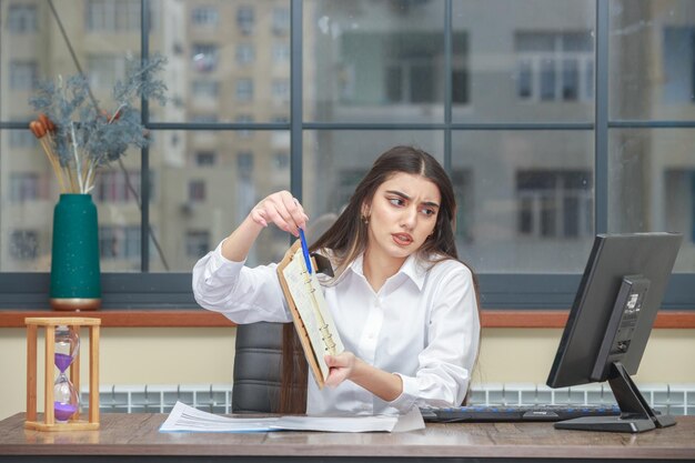 Foto de una joven sosteniendo un cuaderno y mostrándose a la cámara