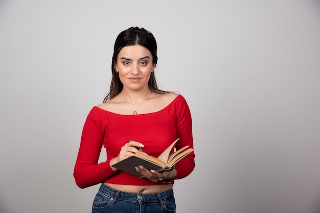 Foto de una linda mujer sosteniendo un libro abierto con un lápiz.