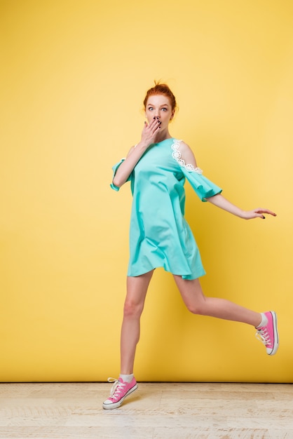 Foto de longitud completa de mujer sorprendida de jengibre en vestido saltando