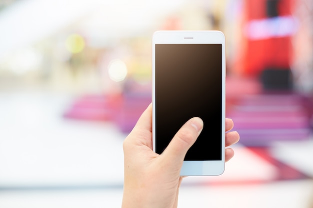 Foto de la mano femenina sostiene el teléfono inteligente con pantalla de copia en blanco para su contenido publicitario o texto promocional