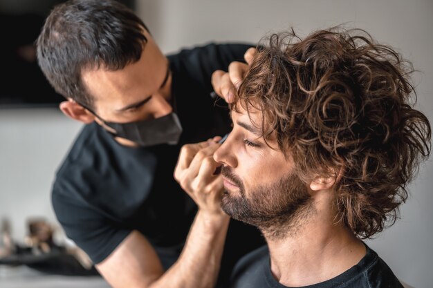 Foto de un maquillador con una máscara médica haciendo su trabajo - nueva normalidad