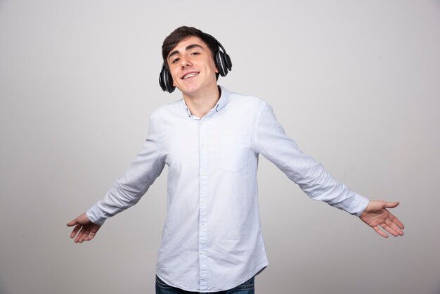 Foto de un modelo de chico feliz escuchando música en auriculares inalámbricos