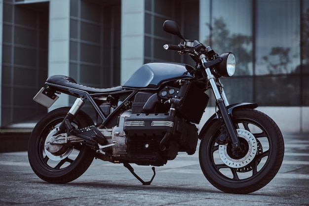 Foto de una motocicleta retro hecha a medida contra un rascacielos.