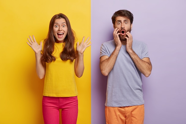 Foto gratuita foto de mujer alegre y emocionada levanta las manos y exclama algo emocionalmente, el hombre sorprendido mira con gran asombro