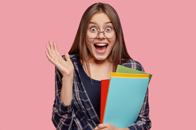 Foto de mujer caucásica asombrada mantiene la palma cerca de la cara, exclama con positividad, feliz de escuchar los buenos resultados del examen