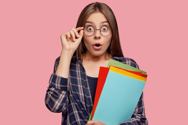 Foto de mujer caucásica sorprendida mira fijamente con ojos saltones