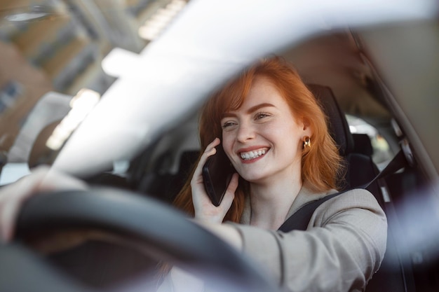 Foto de mujer conductora viajera está hablando por teléfono inteligente detrás del volante del coche