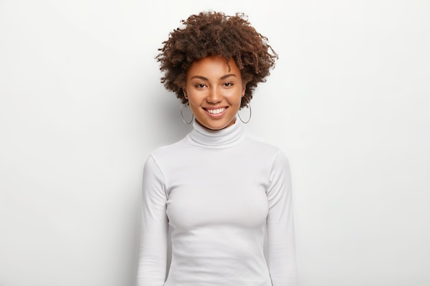 Foto de mujer encantadora carismática con pelo rizado, se divierte, sonrisa con dientes en la cara