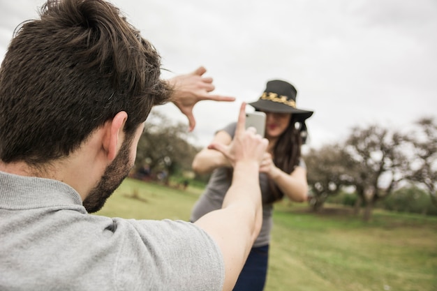 Foto de mujer hablando de un hombre haciendo marco a mano en el parque