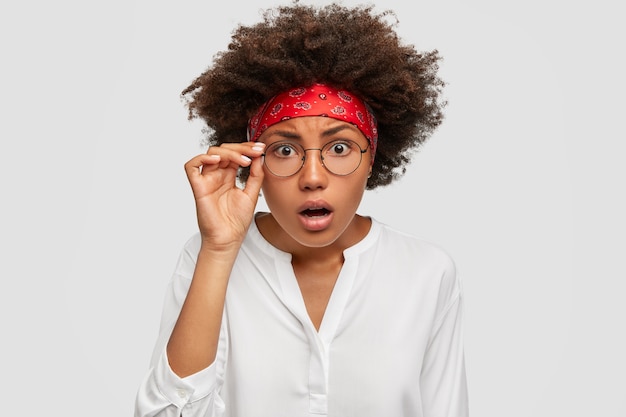 Foto de mujer hermosa aterrorizada mantiene la mano en el borde de las gafas