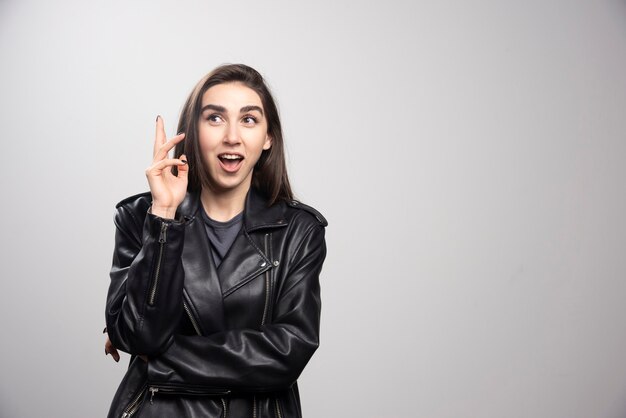 Foto de una mujer hermosa en chaqueta de cuero negro apuntando hacia arriba