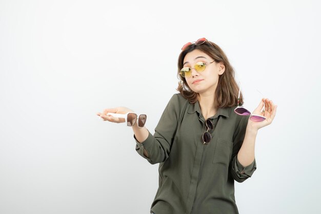 Foto de mujer hermosa con gafas de sol de colores de pie sobre blanco. foto de alta calidad