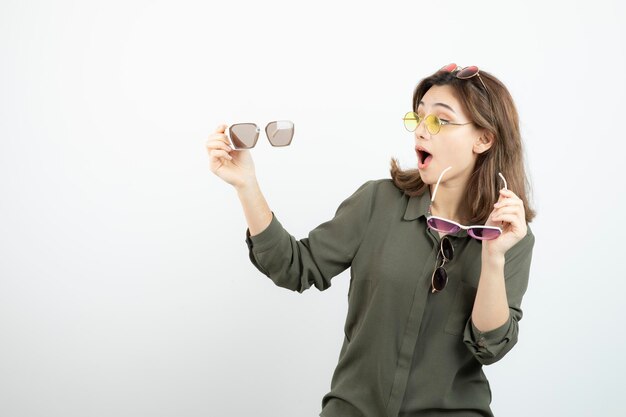 Foto de mujer hermosa con gafas de sol de colores de pie sobre blanco. foto de alta calidad