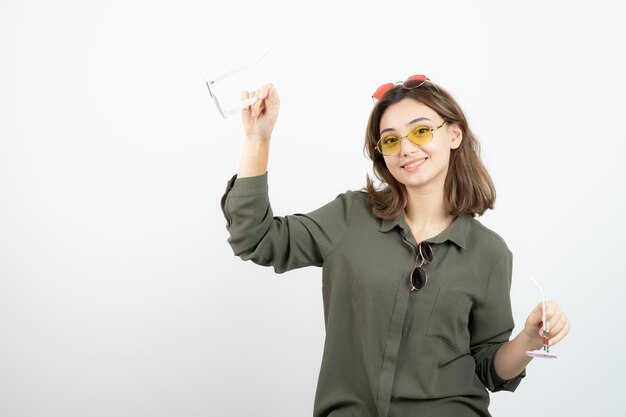 Foto de mujer hermosa con gafas de sol de colores posando sobre blanco. foto de alta calidad