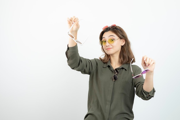 Foto de mujer hermosa con gafas de sol de colores posando sobre blanco. foto de alta calidad