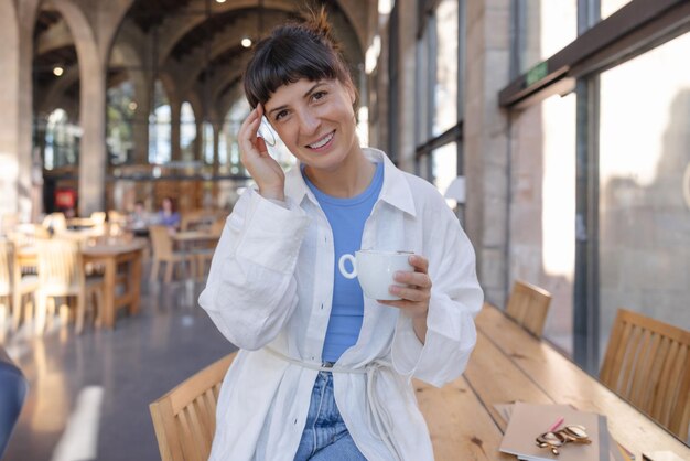 Una foto de una mujer hermosa mira la cámara con una taza de café