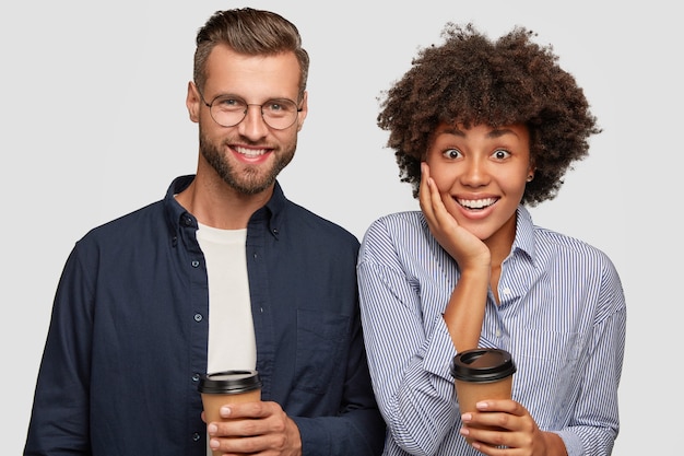 Foto de mujer y hombre de raza mixta satisfechos sostiene una taza de café desechable