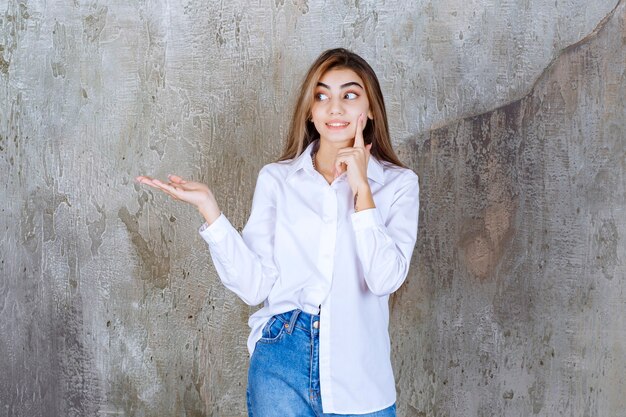 Foto de mujer joven en blusa blanca de pie y mirando