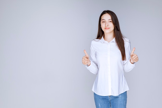 Foto de mujer joven con camisa blanca de pie sobre la pared. Foto de alta calidad