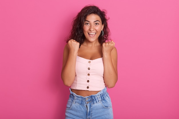 Foto de mujer joven feliz con hermoso cabello ondulado oscuro gritando, vistiendo ropa elegante